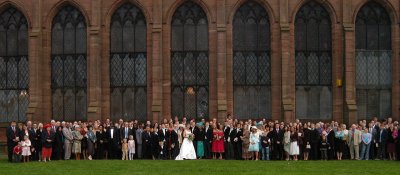 photograph of a large group of people in front of a church at a wedding
